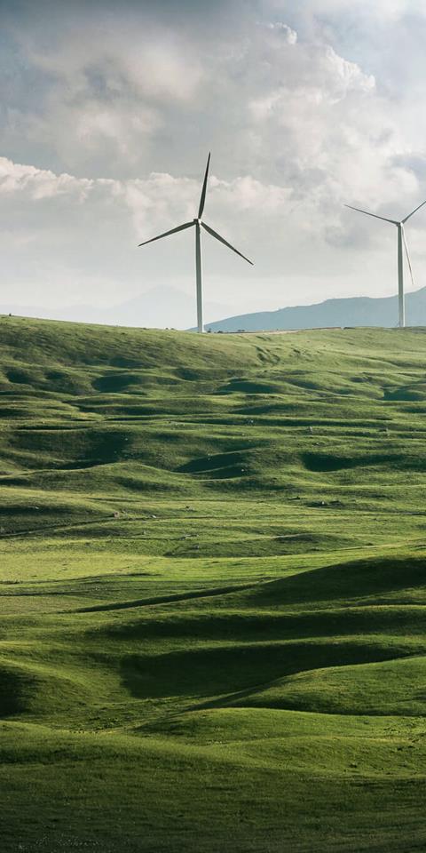 onshore windfarm with turbines on the crest of rolling green hills